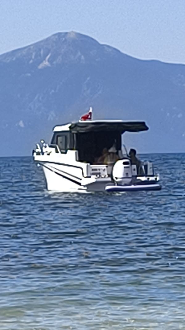 Motorboat flying Turkish flag cruises calm Aegean waters near Kuşadası