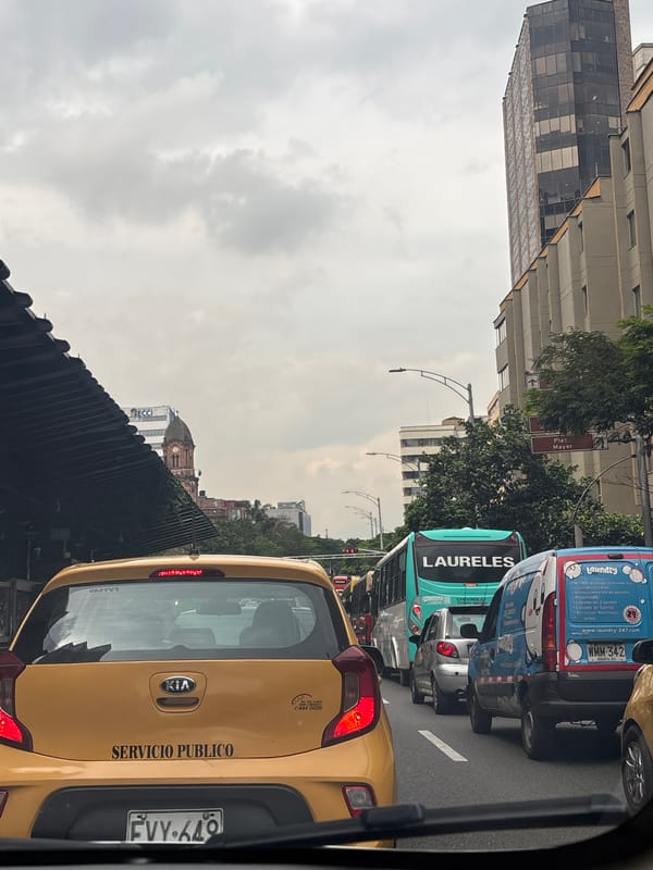 Routine traffic scene captured in Medellín with taxi and bus