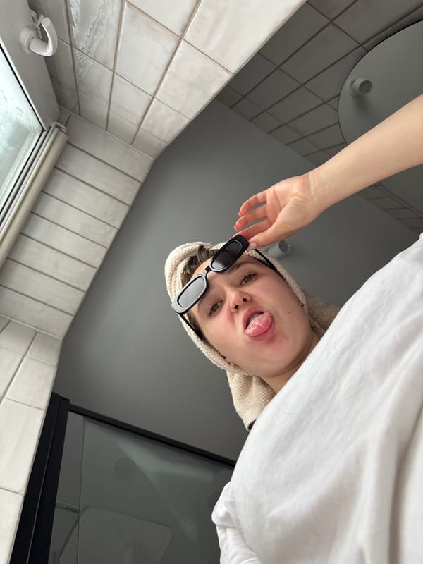 Person poses with towel and sunglasses in Izhevsk bathroom