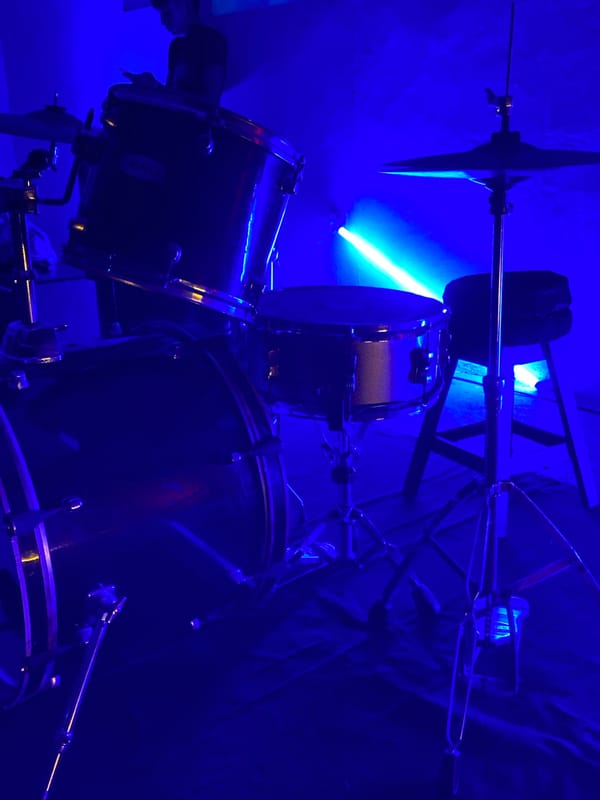 Drum set captured under blue lighting in Tinaquillo room
