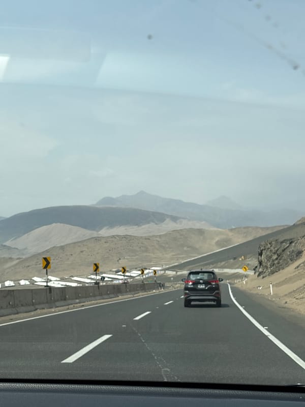 Black car travels road with barriers in Aucallama Peru