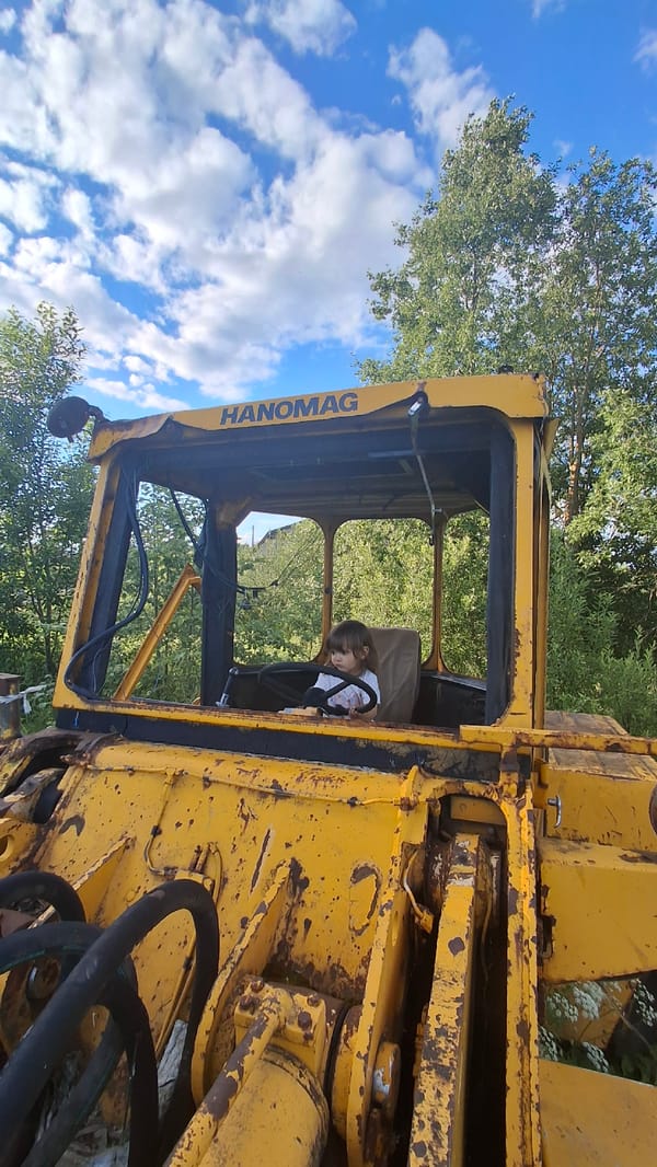 Kid plays in abandoned yellow loader in rural Russian field