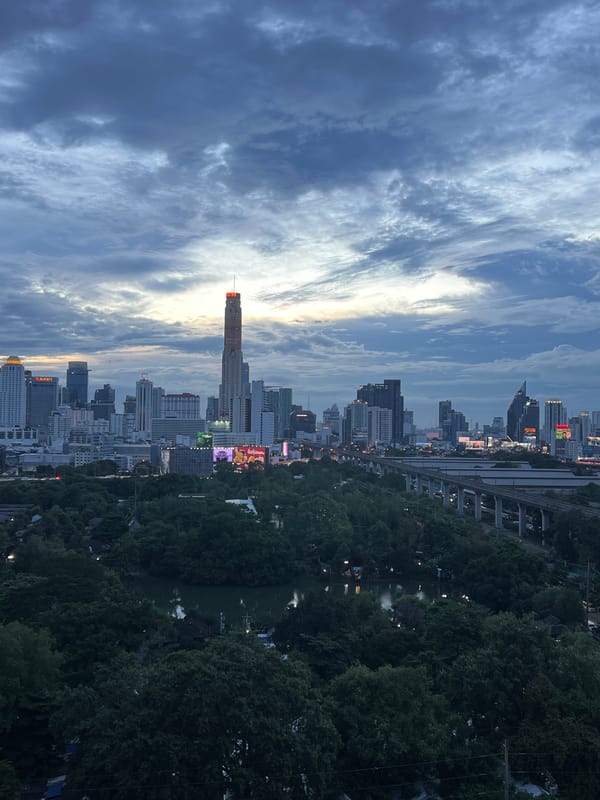 Bangkok skyline silhouetted against a moody dusk sky