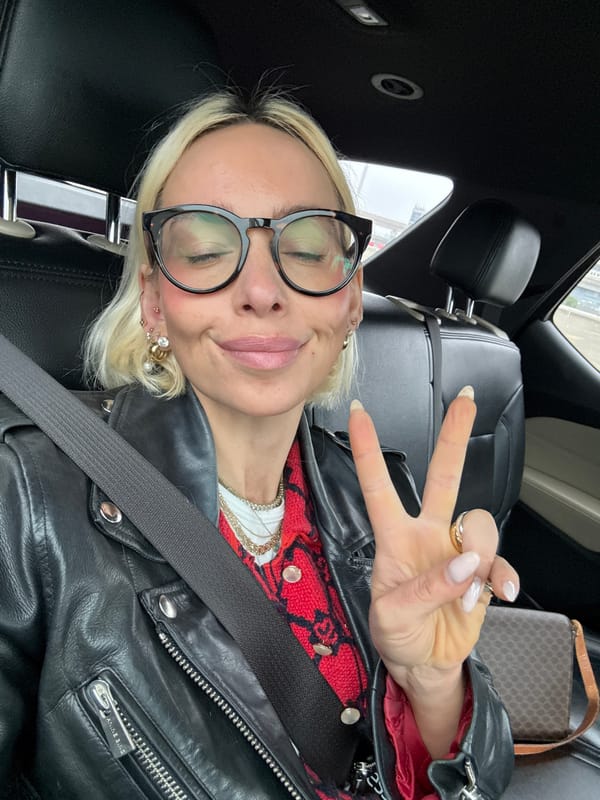 Woman makes peace sign gesture while seated in car