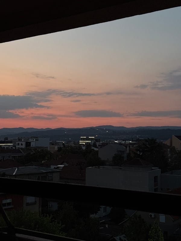 Kragujevac skyline at dusk, mountains silhouetted on the horizon