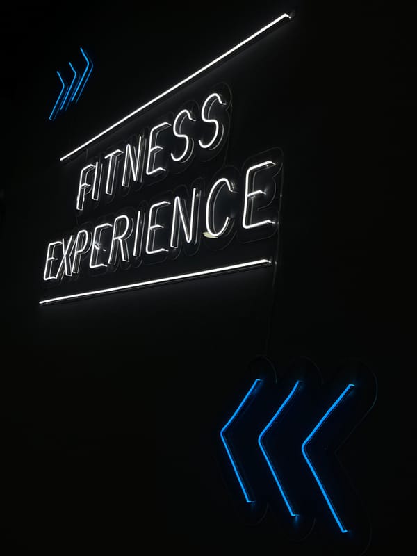 Neon fitness center sign observed in dark setting