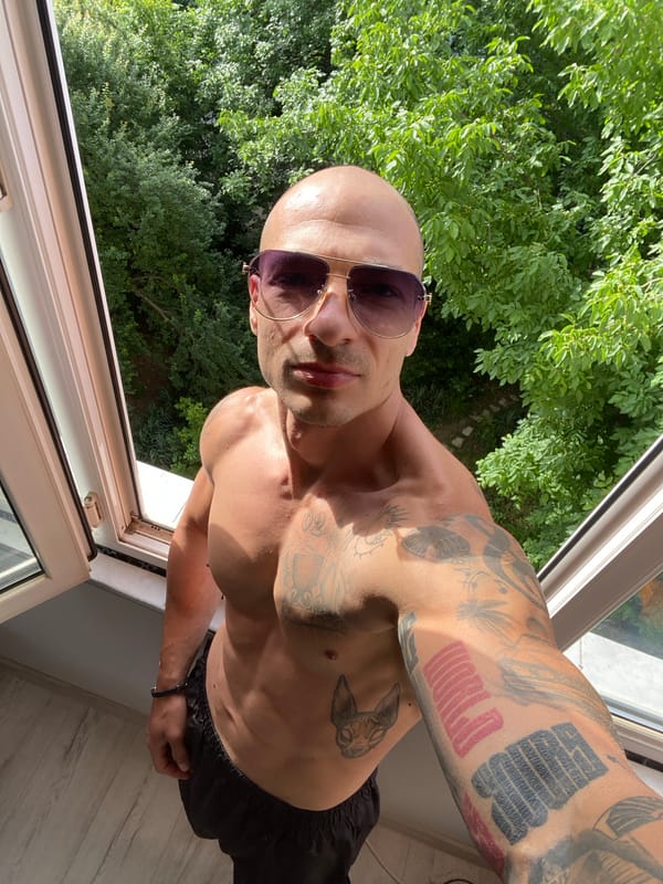 Tattooed figure poses in apartment window, Pleven