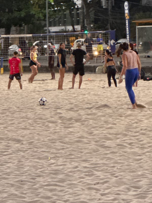 Evening beach life in Niterói — soccer, jogging, and city backdrop