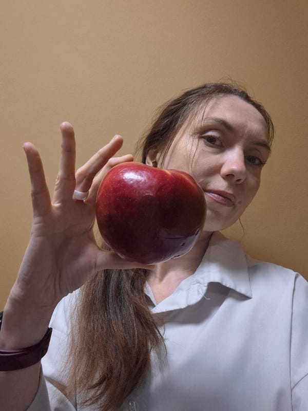 Woman photographed holding red apple from low angle perspective