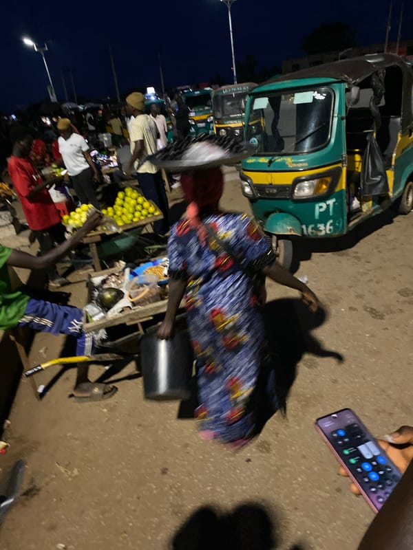 Bukuru street life at dusk: markets, traffic, and loaded vehicles