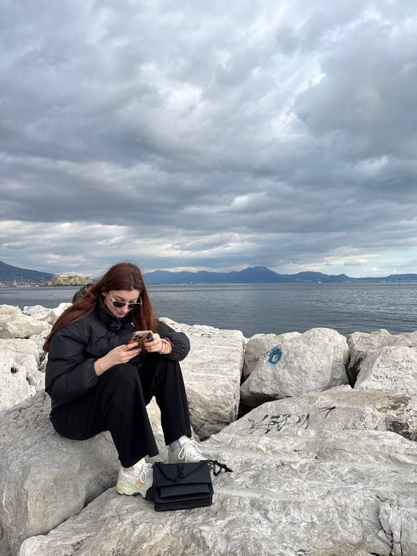 Woman sits on Naples breakwater under overcast skies