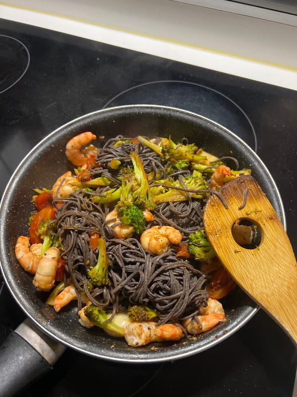 Woman documents cooking dark pasta meal in Paris kitchen