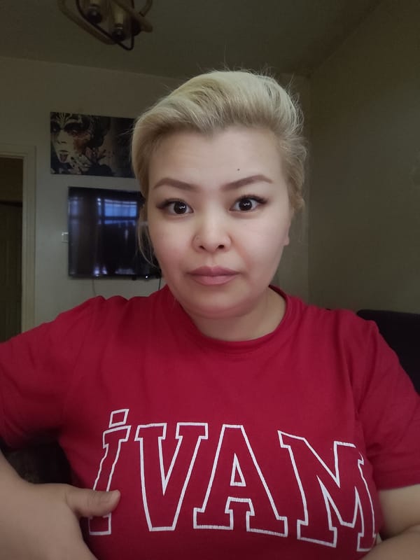 Woman in red IVAN shirt pets white cat indoors