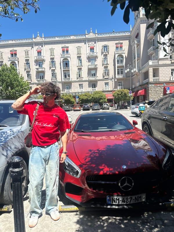 Young man poses with red Mercedes sports car around Tbilisi