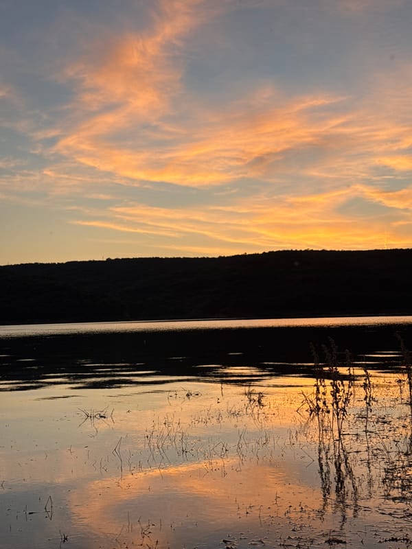 Sunset over Bulgarian waterway, hillside in silhouette