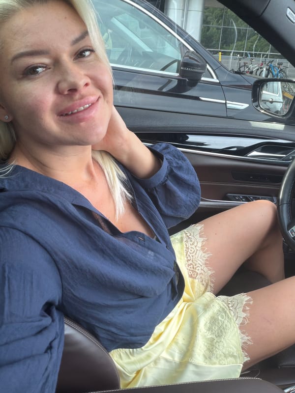 Smiling from the driver's seat of a parked car
