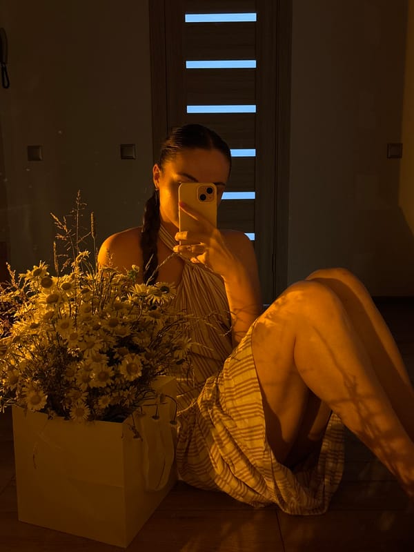 Mirror selfies on a wooden floor with a daisy bouquet nearby