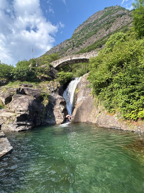 Person enjoys waterfall swim at Biasca rock formation