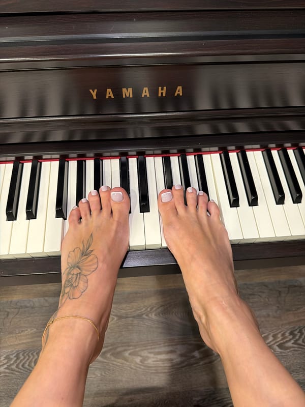 Bare feet with painted nails rest on piano keys