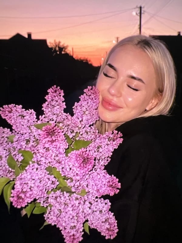 Woman poses with lilac flowers in peaceful portrait session