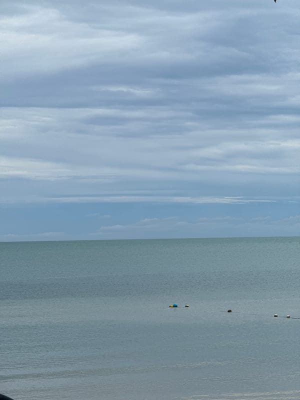Calm coastal day with boats, beaches, and overcast skies