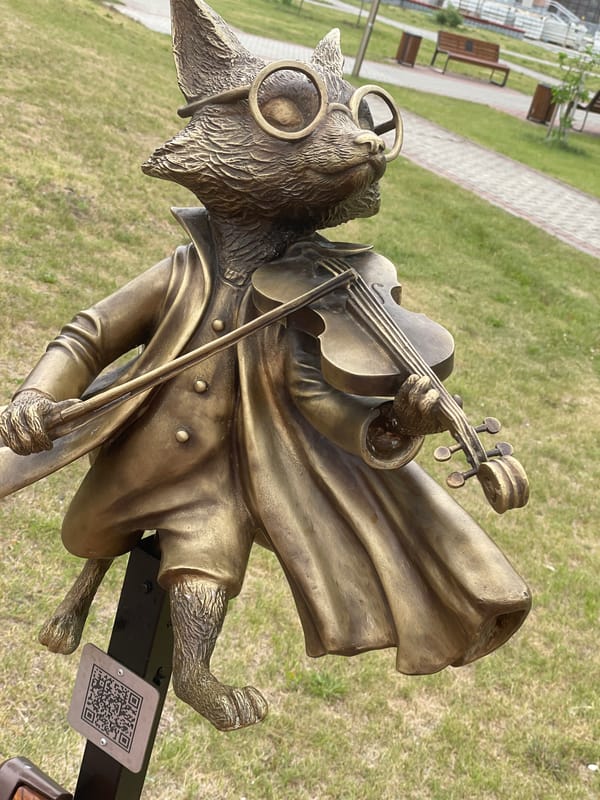 Bronze violin-playing cat and begonias in Surgut