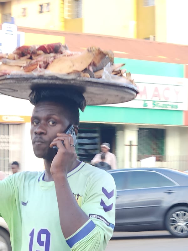 Street vendors balance goods on their heads in a busy urban market