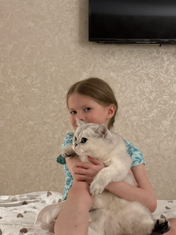 Girl reads children's book with white cat in Izhevsk bedroom