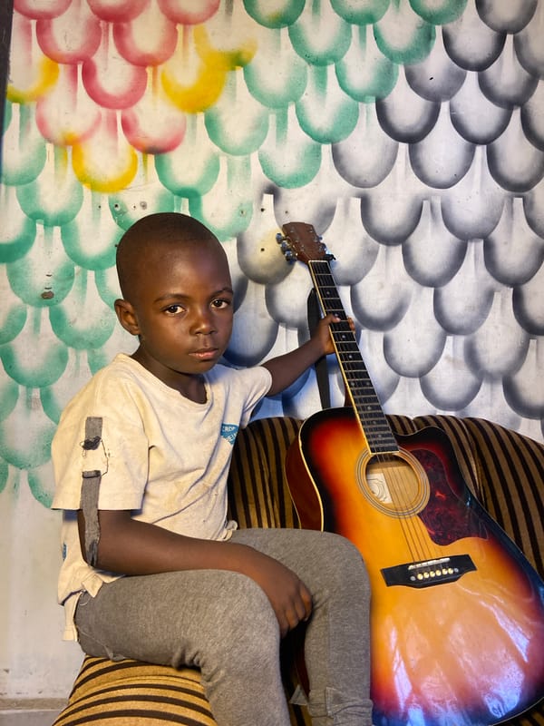 Young boy poses with acoustic guitar in Mararaba, Nigeria