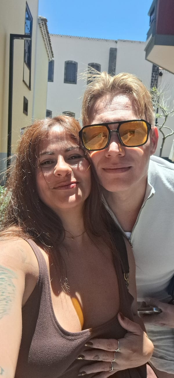 Two friends take selfies near bell tower on sunny day