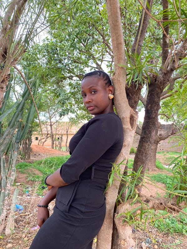 Woman poses with flowers among trees in Nigeria