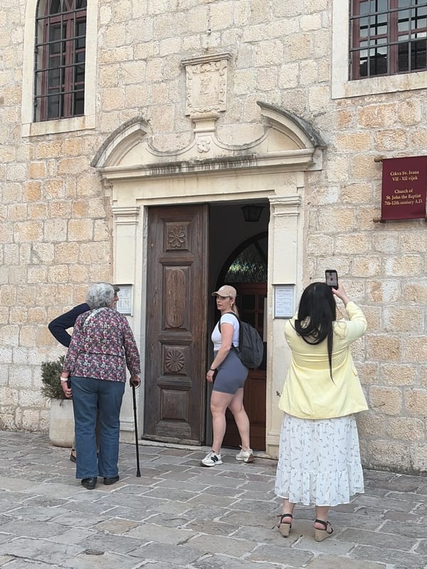 Three women embrace near historic church in Budva, Montenegro
