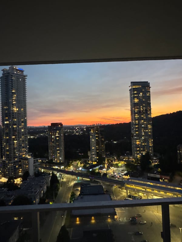 Coquitlam skyline glows at dusk from a balcony view