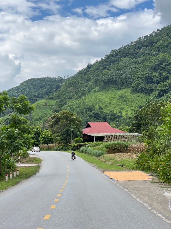 Winding mountain road past a red-roofed building in Thuận Hòa