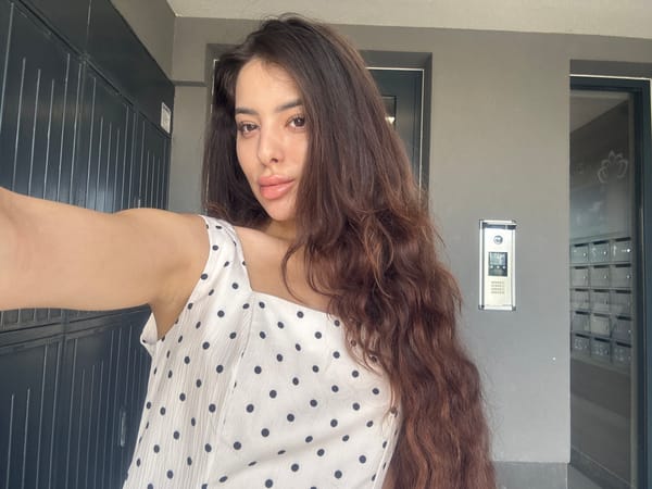 Woman takes selfies in polka-dot dress on Plovdiv sidewalk