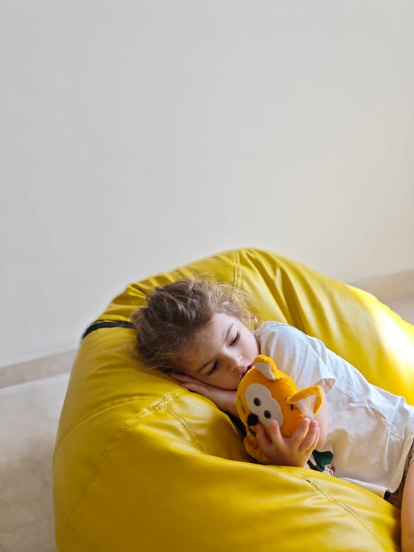 Child rests with stuffed toy on beanbag in Mumbai