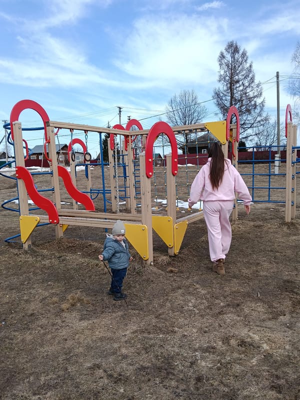 Woman and child at playground in early spring Russia