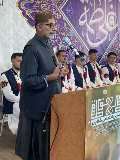 Traditional-dressed speaker addresses audience in decorated Quetta venue