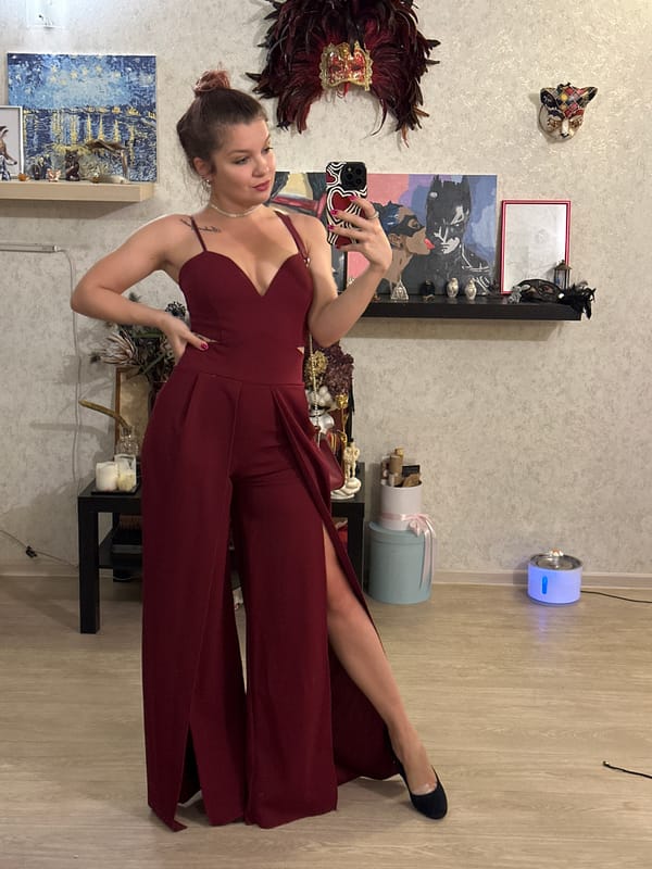 Woman takes selfie in maroon jumpsuit near decorative display