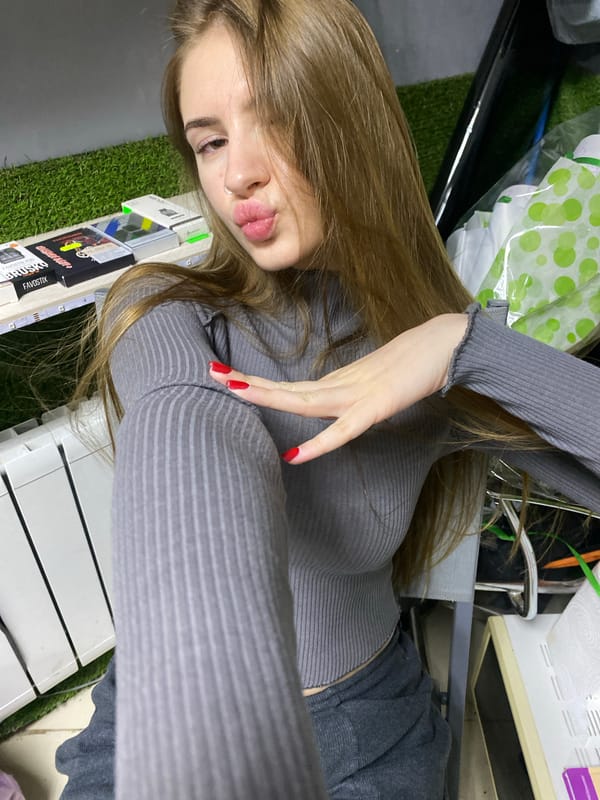 Woman takes selfies in grey sweater in Russian village