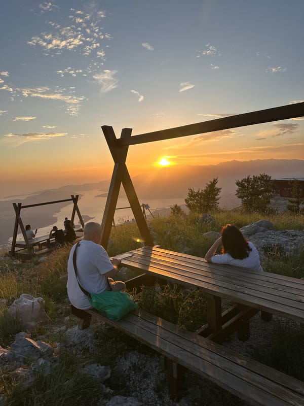 Couple watches sunset from mountain overlook in Montenegro