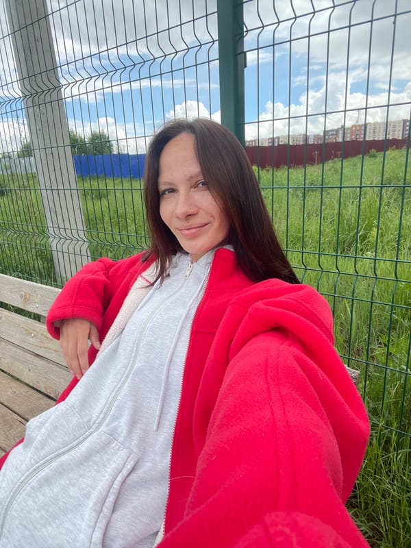 Woman sits smiling on bench in Izhevsk park