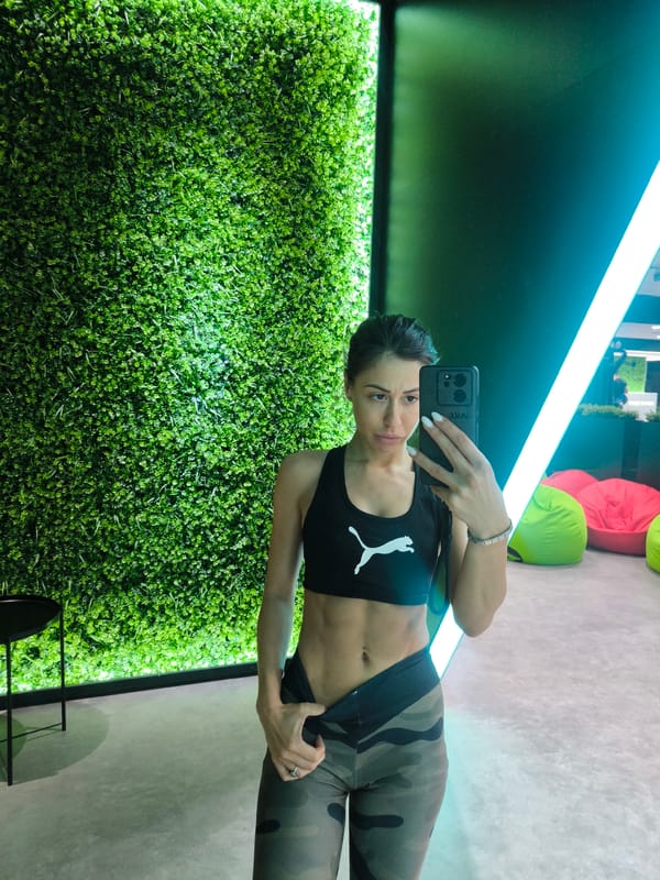 Person takes selfie against decorative wall with green foliage