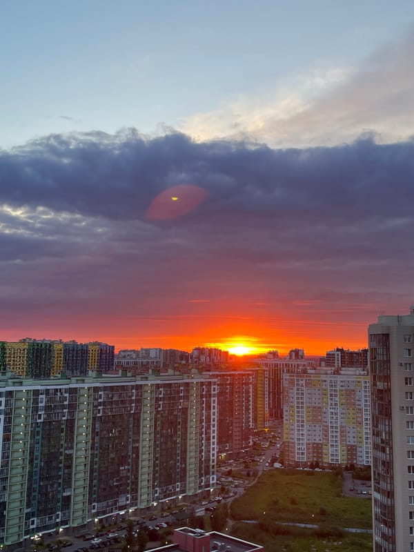 City skyline framed by a vivid, crescent-moon sunset