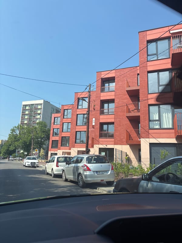 Driving through a quiet Kraków neighborhood past shops and parcel lockers