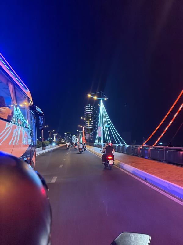 Nighttime traffic observed near illuminated bridge in Nha Trang