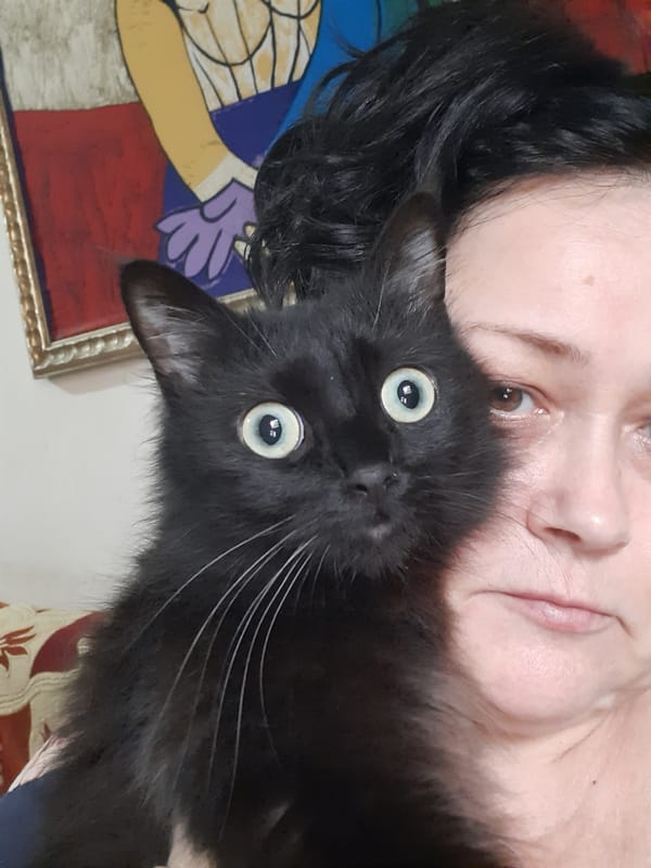 Person poses with black cat in Al Hadaba home