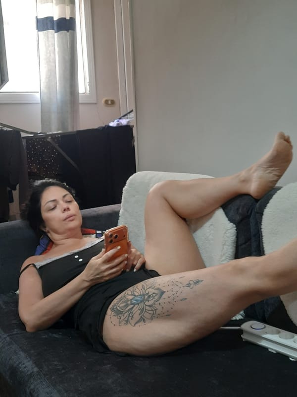 Woman rests on couch with phone in Al Hadaba