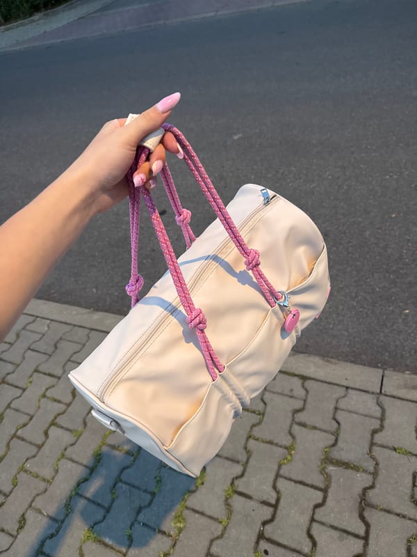 Beige cylindrical bag and black sandals on concrete pavers