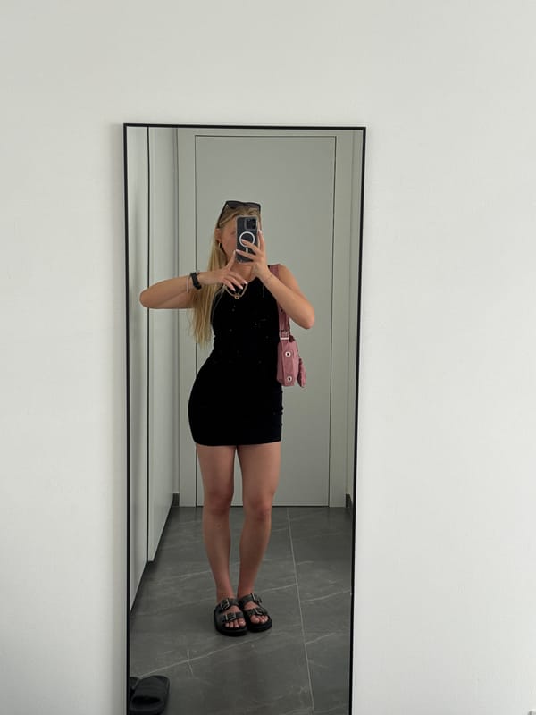 Person takes mirror selfie in black dress, Ariel